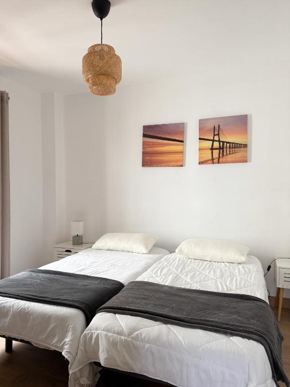 two beds in a white room with two pictures on the wall at El Puertito Beach Retreat in Agaete