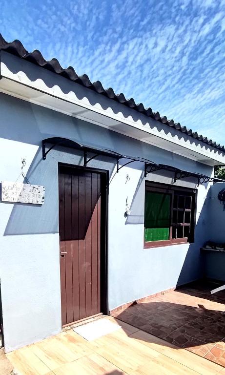 a white house with a brown door and a window at Kitnet da Elô in Tramandaí