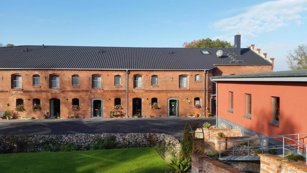 a large red brick building with a yard at Pension Am Dorfanger in Hohennauen