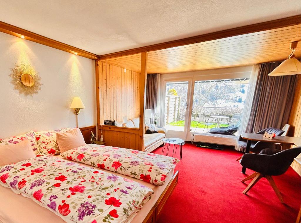 a hotel room with a bed and a large window at Adelhome Studio mit Gartensitzplatz in Adelboden