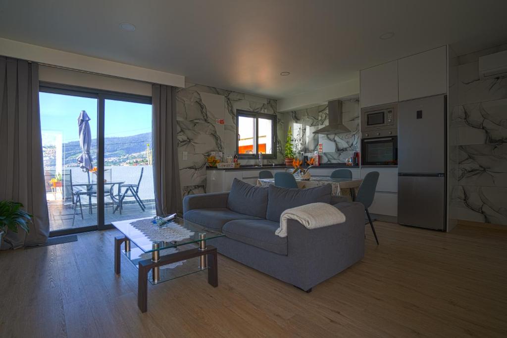 a living room with a blue couch and a kitchen at Moonfall House in Arco da Calheta