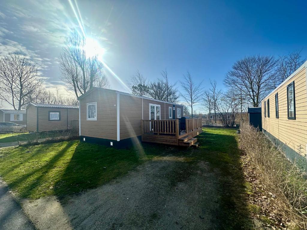 a tiny house with a deck on a yard at Chalet Levy in Lauwersoog