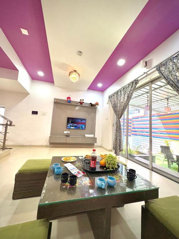 a living room with a table and purple ceilings at SilverOak 4bhk Villa in Jāmb