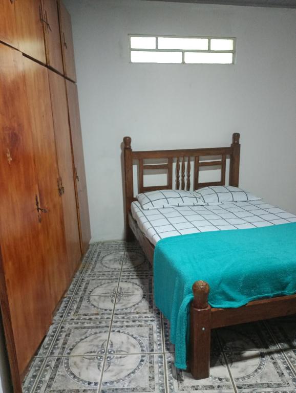 a bedroom with a bed and a wooden cabinet at casa aconchegante para descansar in Alegrete