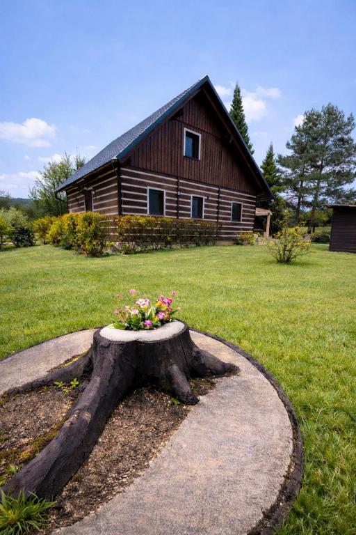 a tree stump with a flower arrangement on it in front of a house at Chaloupka v ráji in Veselá