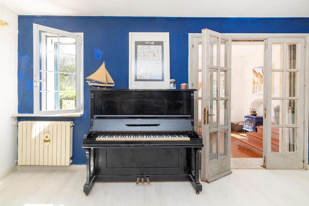 a black piano in a room with a blue wall at Ca du Aldo - La Crema in Finale Ligure