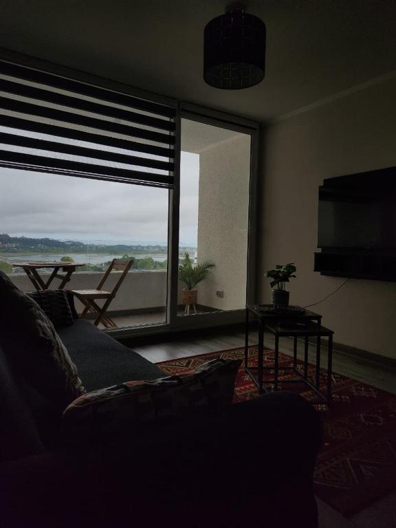 a living room with a couch and a large window at Departamento Concepción in Concepción