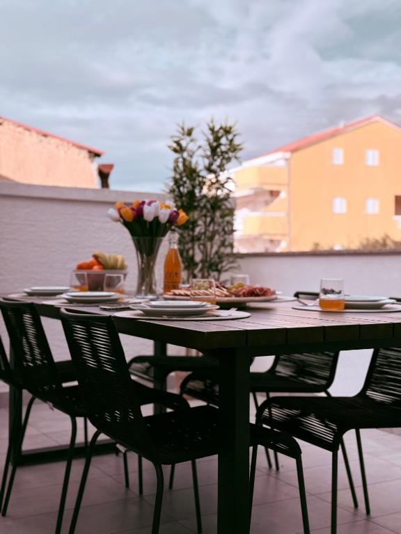 a table with chairs and food on a patio at Apartments Pablo Novalja in Novalja