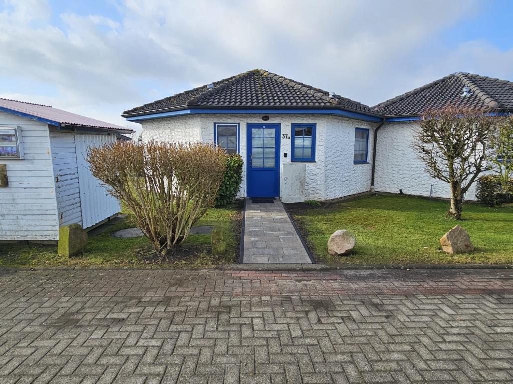 a white house with a blue door at Ferienhaus Meeresbrise in Wurster Nordseeküste