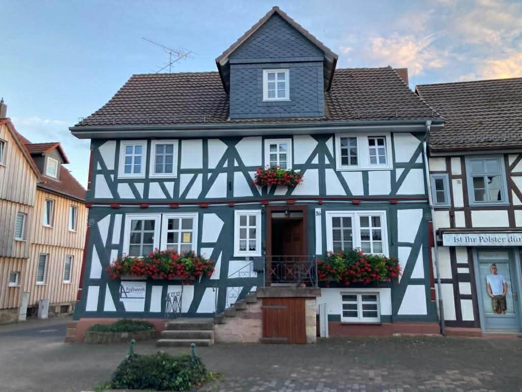 a black and white building with flowers in front of it at Ferienwohnung Lukas in Frielendorf