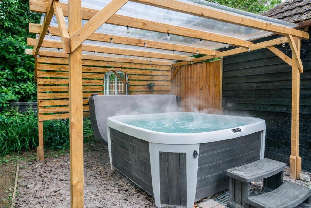 a hot tub in a backyard with a pergola at New Forest Cottage with Hot Tub, Fireplace and Private Garden in Cadnam