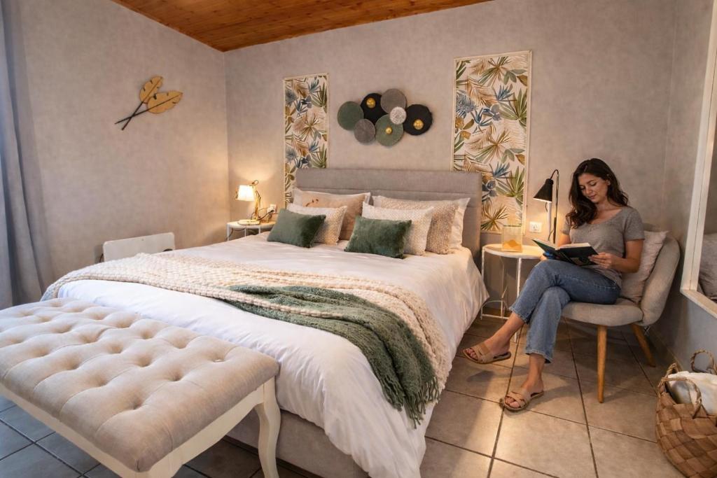 a woman sitting on a chair in a bedroom with a bed at Nafplio Cottage-Grandma's Yard in Asíni