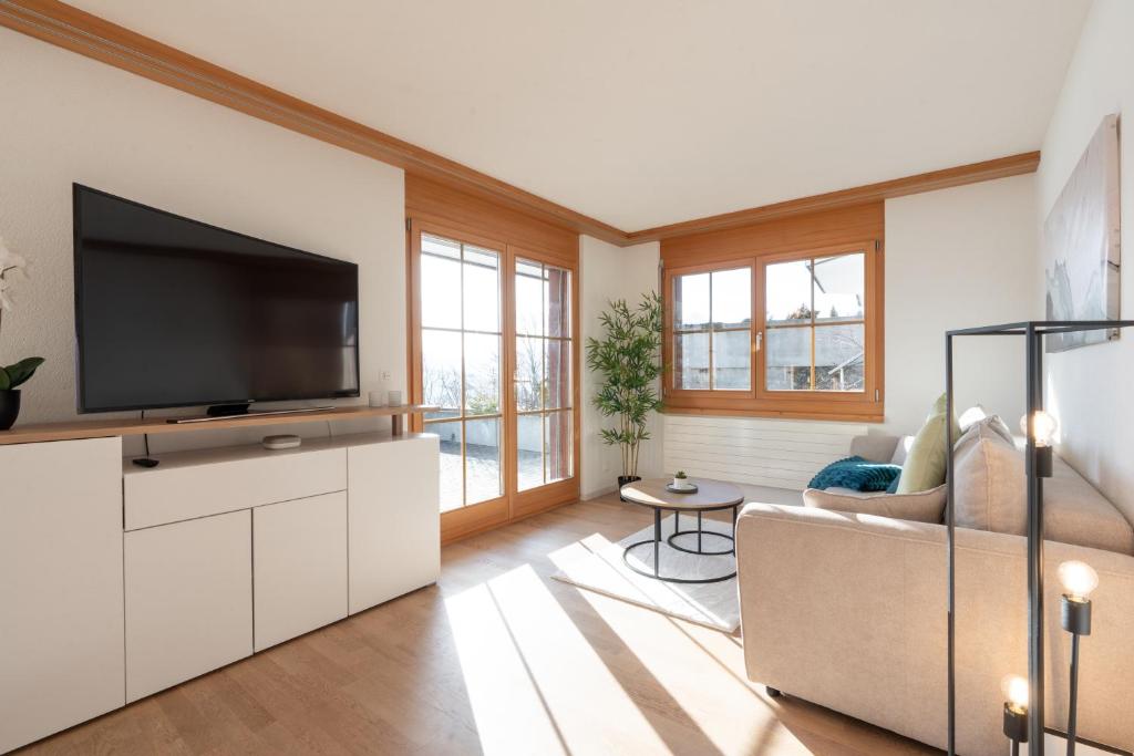 a living room with a television and a couch at Alpenblick in Beatenberg