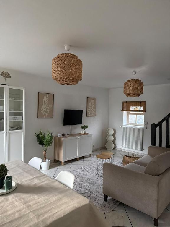 a living room with a couch and a television at Appartement Maisonnette pour 4 personnes in La Ferté-Vidame