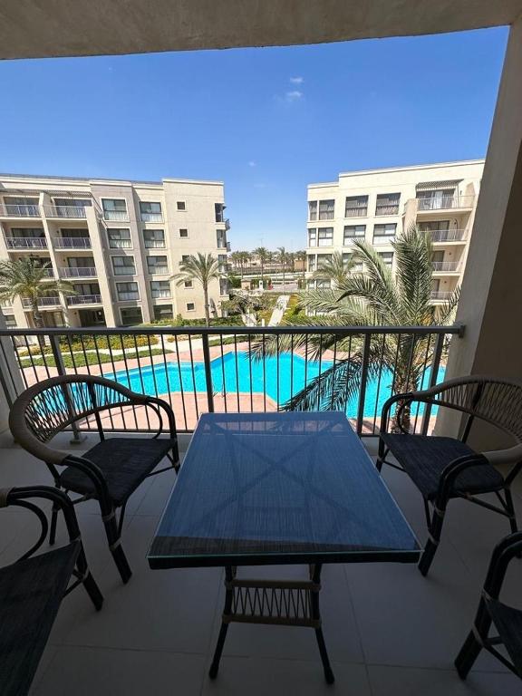 a balcony with a table and chairs and a swimming pool at Marina Marassi in El Alamein