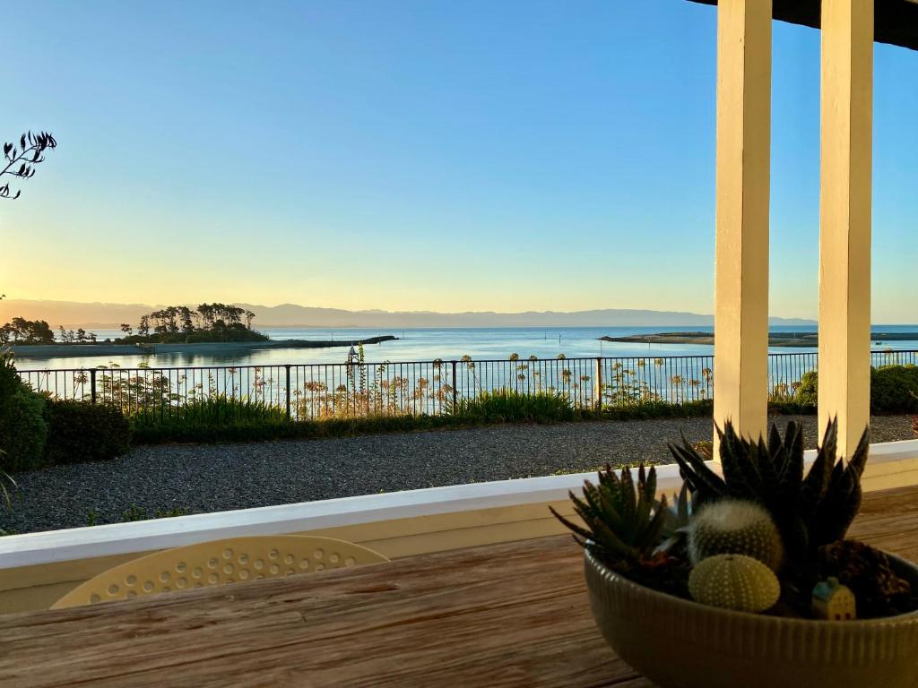 a view of the ocean from a porch with a bowl of pineapple at Villa Victoria - Nelson in Nelson