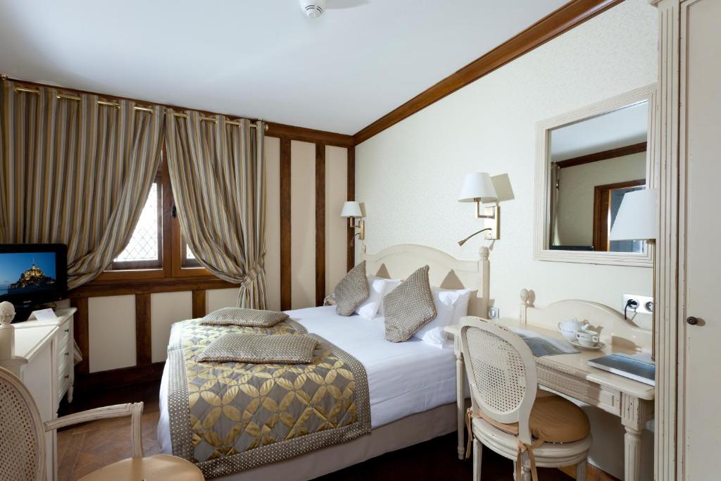 a bedroom with a bed and a desk and a computer at Auberge Saint Pierre in Le Mont Saint Michel