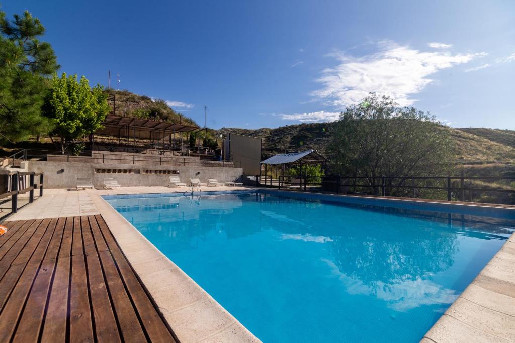 a large blue swimming pool with a wooden deck at CABAÑAS EL CERRO in Ciudad Lujan de Cuyo