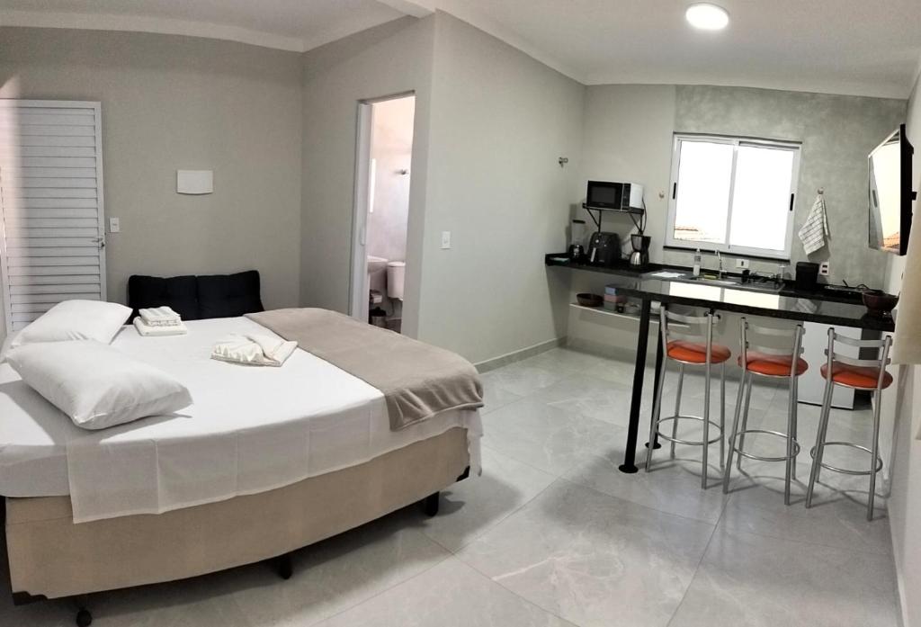 a bedroom with a large bed and a kitchen at Kitnet Moderna com Ar, Garagem e Wi-Fi Rápido in Votorantim