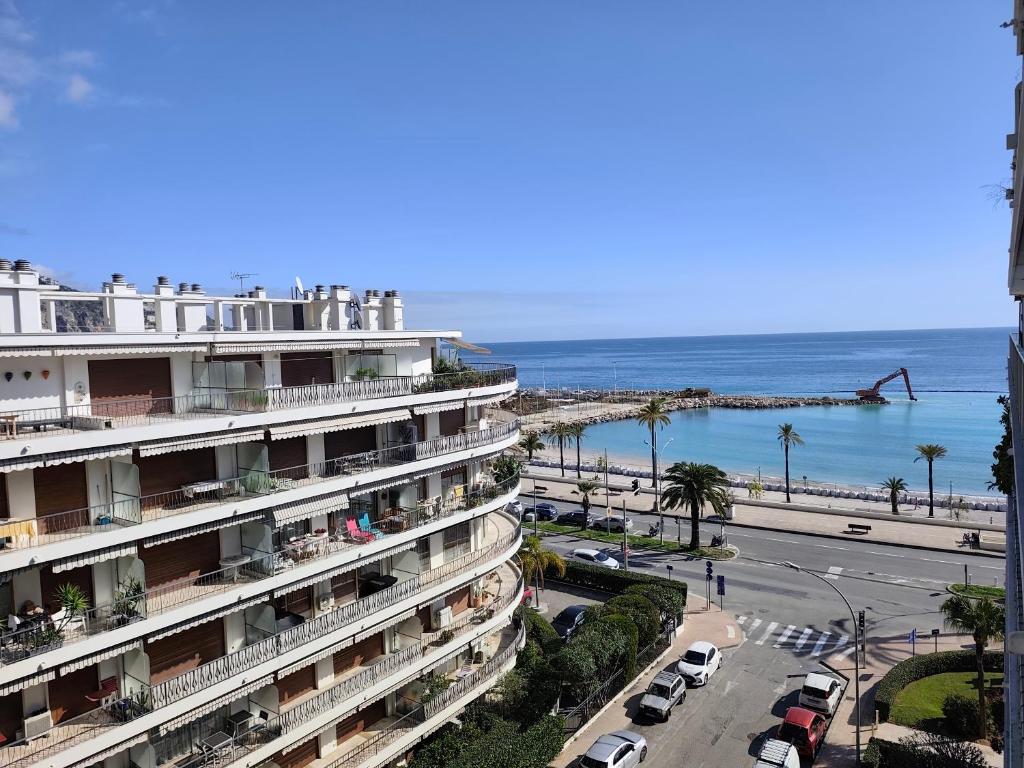 a building next to a beach with cars parked at Sea View Apartment - Residence Les Sablettes in Menton