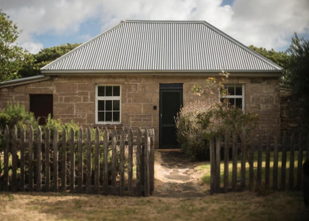 a brick house with a fence in front of it at Devlin's Cottage in Cape Bridgewater