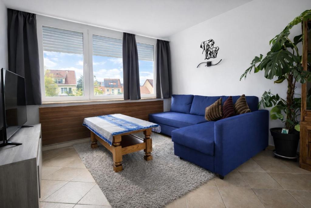 a living room with a blue couch and a table at cozy studio Brussels airport in Steenokkerzeel