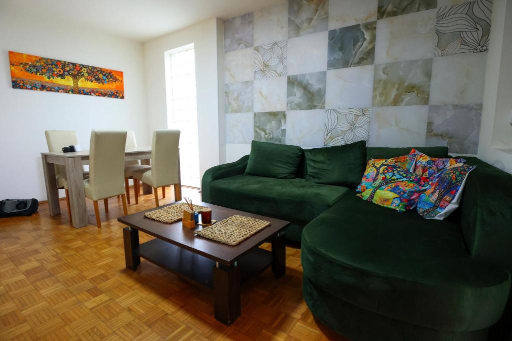 a living room with a green couch and a table at BGD Rentals in Donji Milanovac