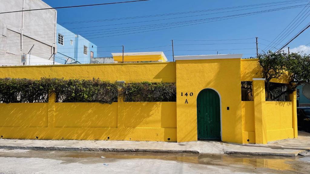 a yellow building with a green door on a street at Casa Bugambilia Progreso #1 in Progreso