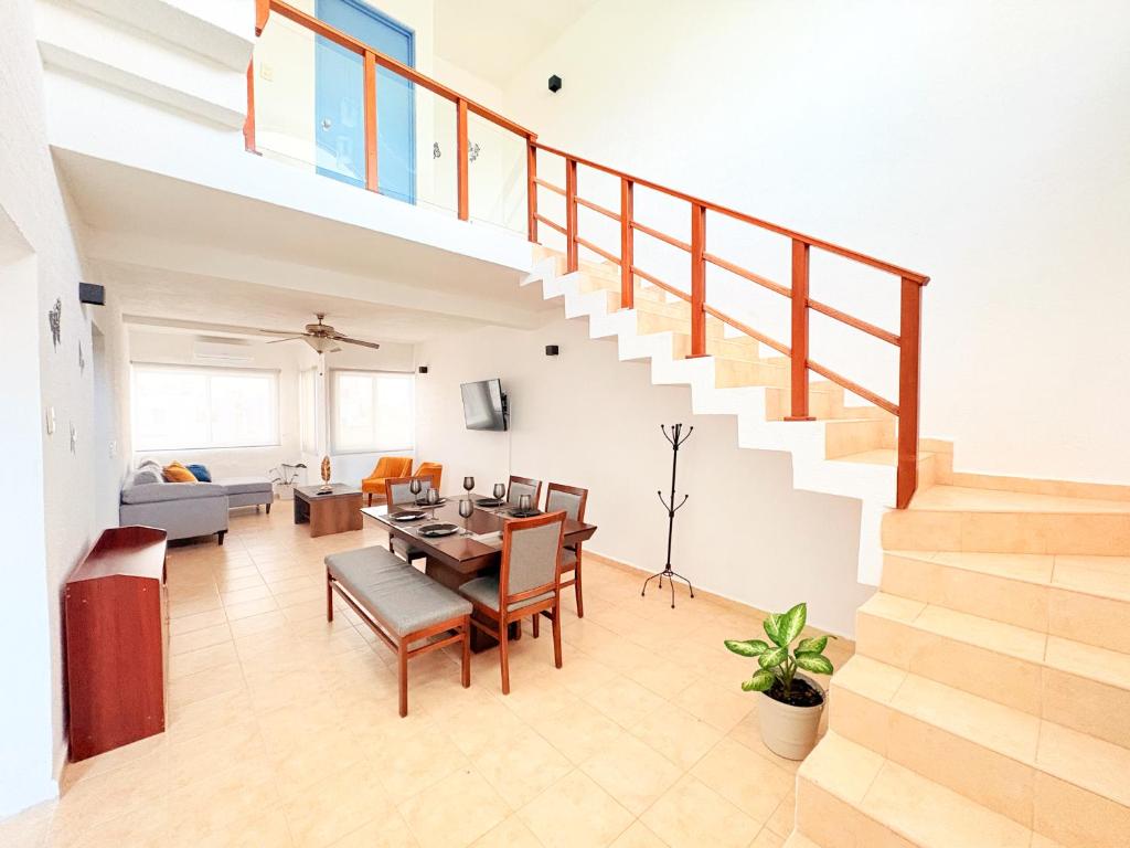 a living room with a staircase and a dining room at Estrella Azul Penthouse in Cancún