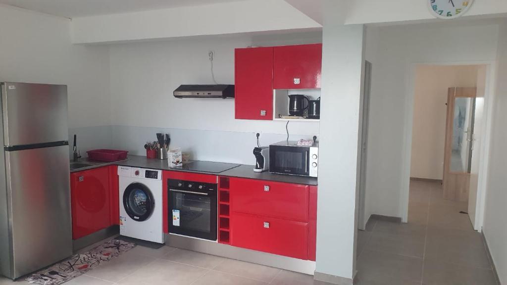 a kitchen with red cabinets and a washer at Appartement Ti Coquelicot in Rivière-Salée