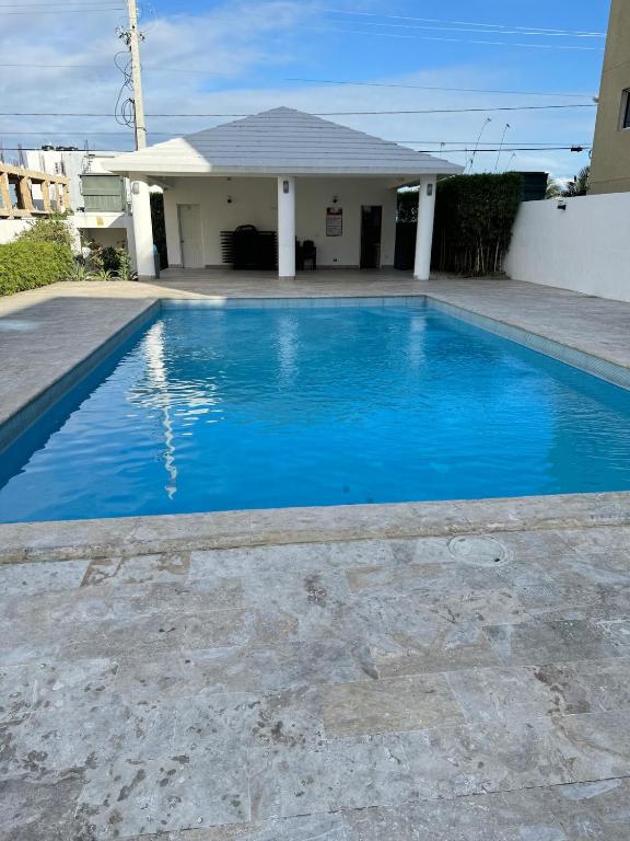 a blue swimming pool in front of a house at Estilo y comodidad a pasos de la playa in La Romana