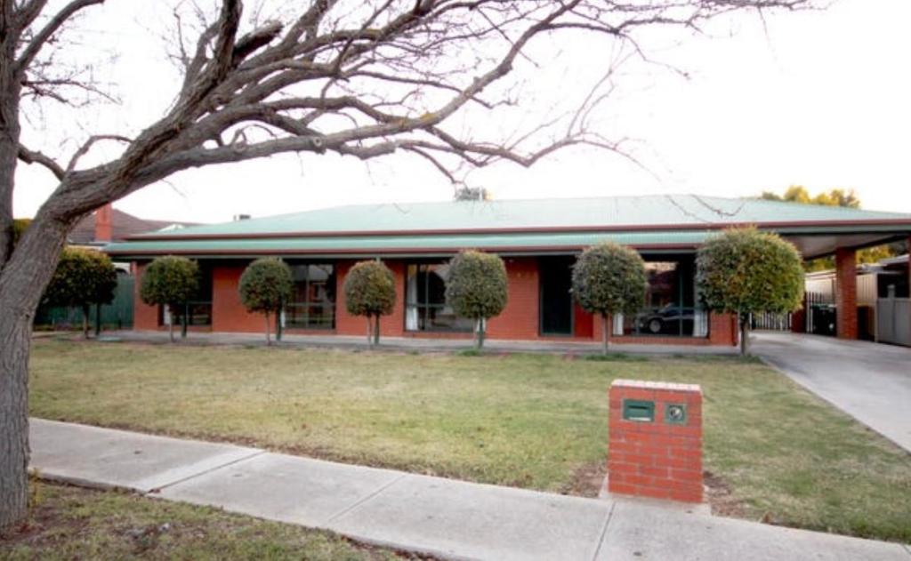 a red building with a tree in front of it at Manor on McIntyre in Horsham