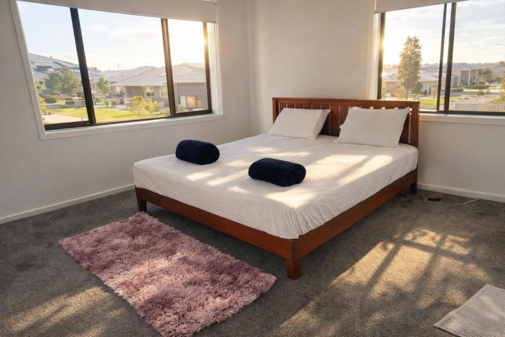 a bedroom with a bed with two pillows on it at Spacious Private 4BR Upper Floor Sleeps 8 Spa Free parking in Werribee