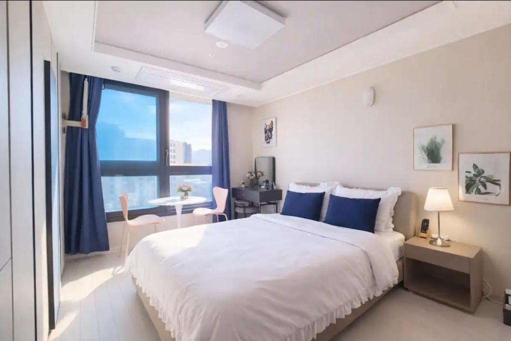 a white bedroom with a large bed and a desk at 대구 동성로 스타비앤비 in Hyomoktong-Ilgu