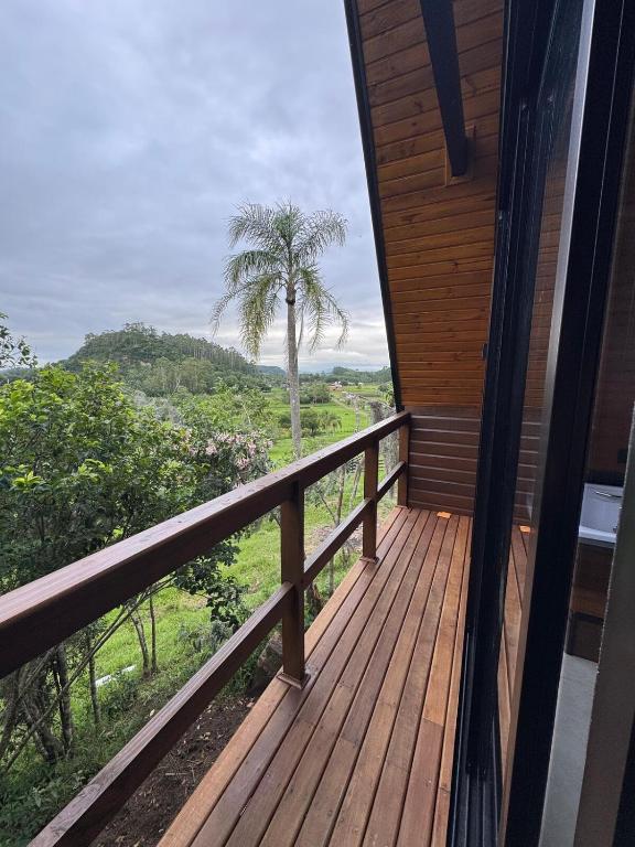 a wooden balcony with a palm tree in the background at Refúgio do Morro - cabana 2 in Torres