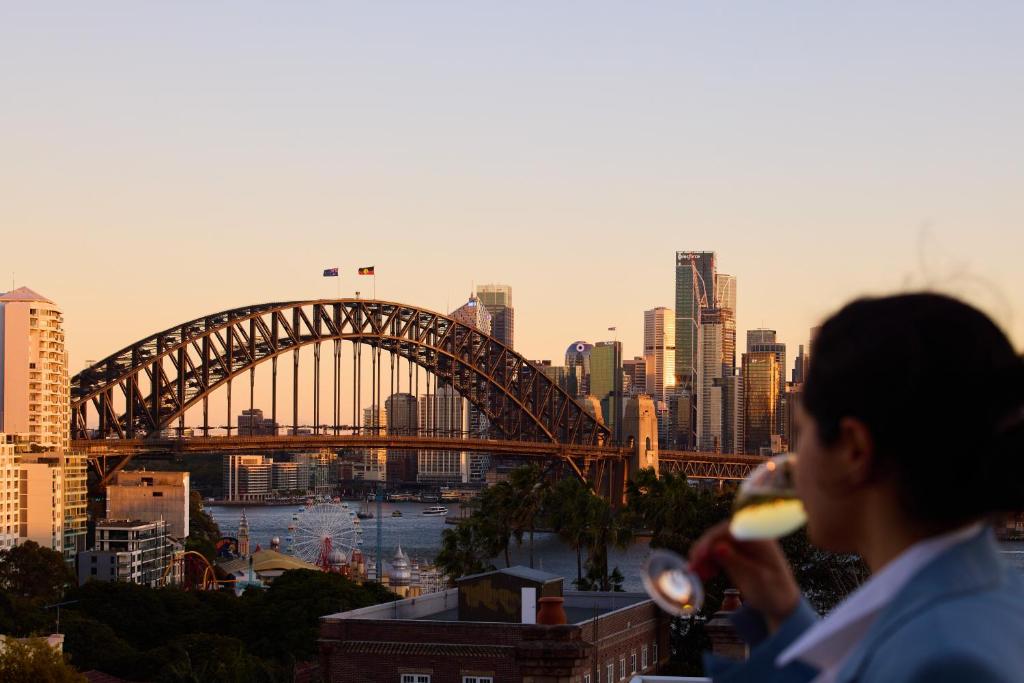 a woman drinking a glass of wine in front of a bridge at View Sydney in Sydney