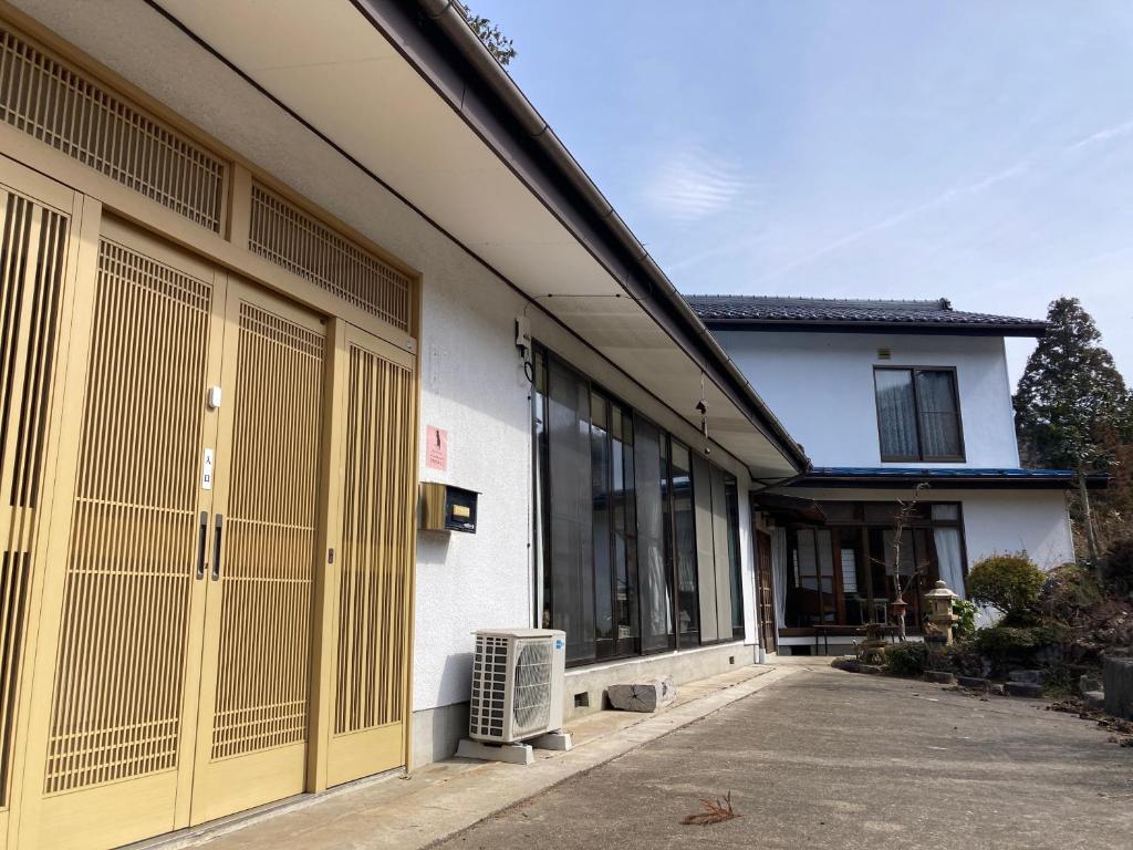 a white building with yellow doors and windows at 民泊ひなたぼっこ1日1組限定離れ貸切 in Nagano