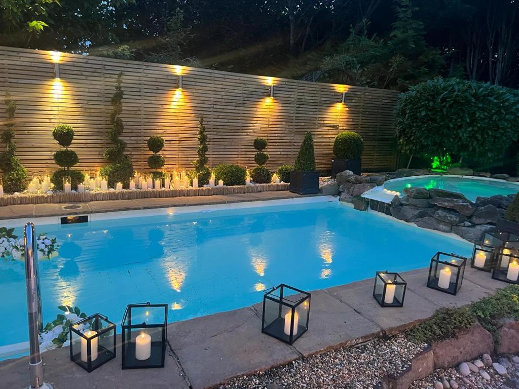 a swimming pool with lights in a backyard at night at The Luxe Pool House, Westoning in Westoning
