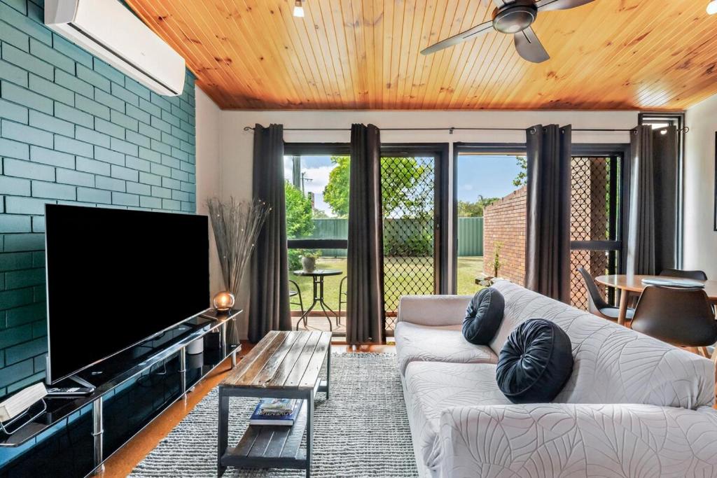 a living room with a couch and a flat screen tv at Pukeko Guesthouse - Relax in Redcliffe in Redcliffe