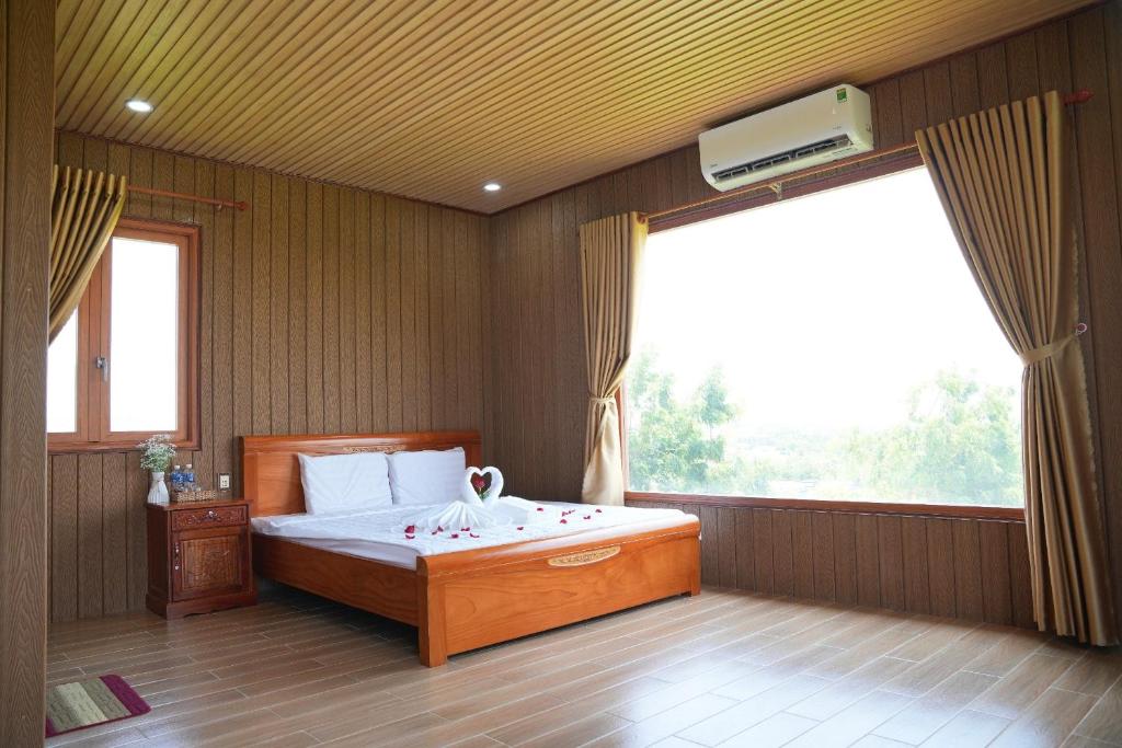 a bedroom with a bed and a large window at Bàu Trắng Garden in Ấp Nhơn Hòa