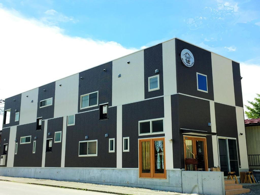 un edificio blanco y negro con un reloj en él en ホステル富士山 結, en Fujiyoshida