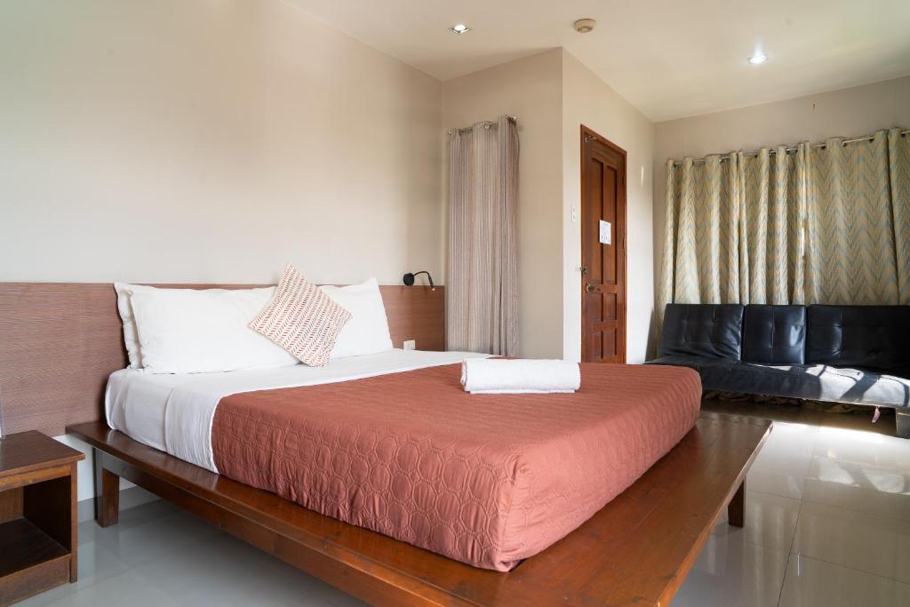 a bedroom with a large bed and a couch at Madonna Hometel and Suites in Panabo