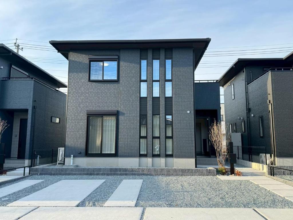 a black brick house with a roof at Akikawa Koshi 13 新築木造一棟貸切ヴィラ in Yuge