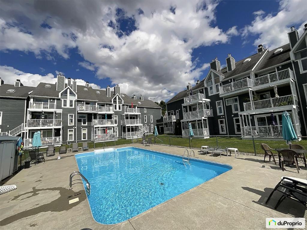 a swimming pool in front of some apartment complexes at La Première vue in Magog-Orford
