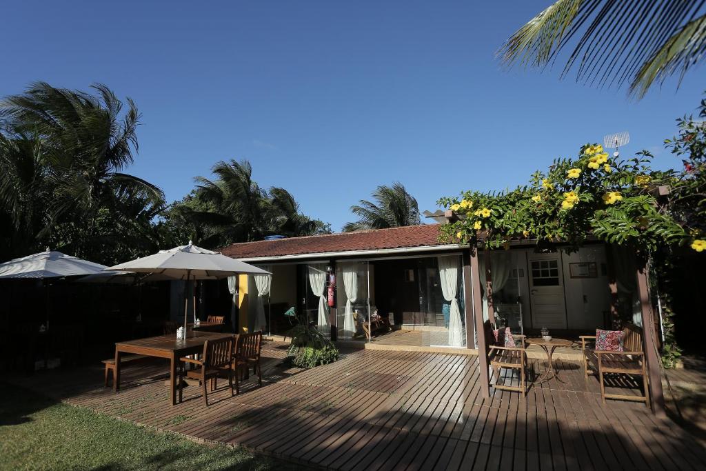 ein Haus mit einer Holzterrasse mit Tischen und Sonnenschirmen in der Unterkunft Pousada Ilha do Frade in Fernando de Noronha