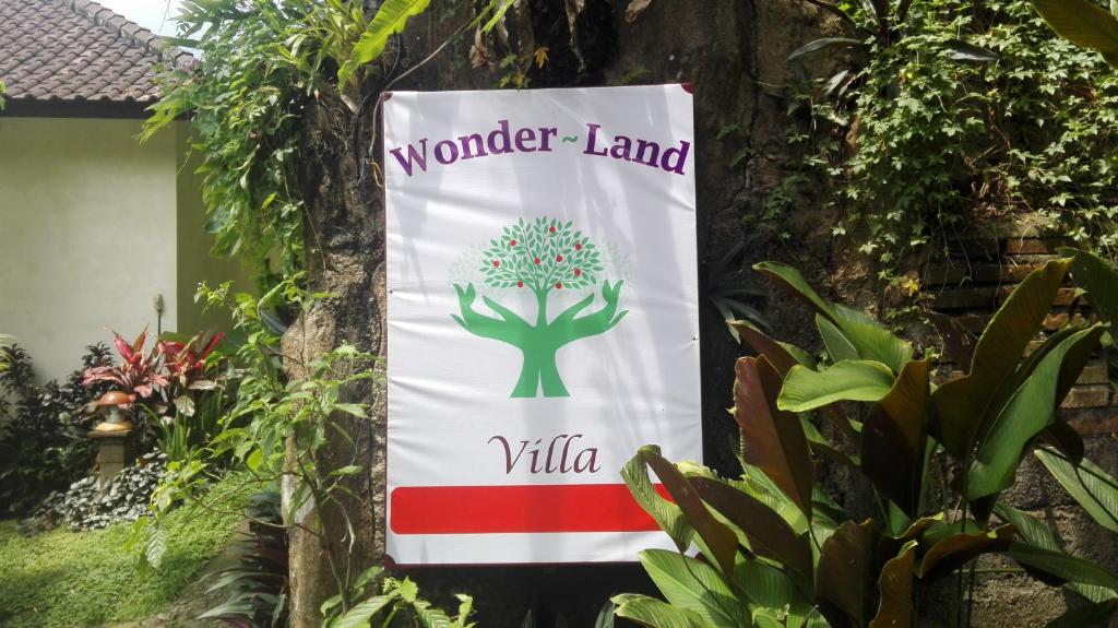 een teken voor het wonderland dorp hangend aan een boom bij Wonder-Land Villa in Ubud