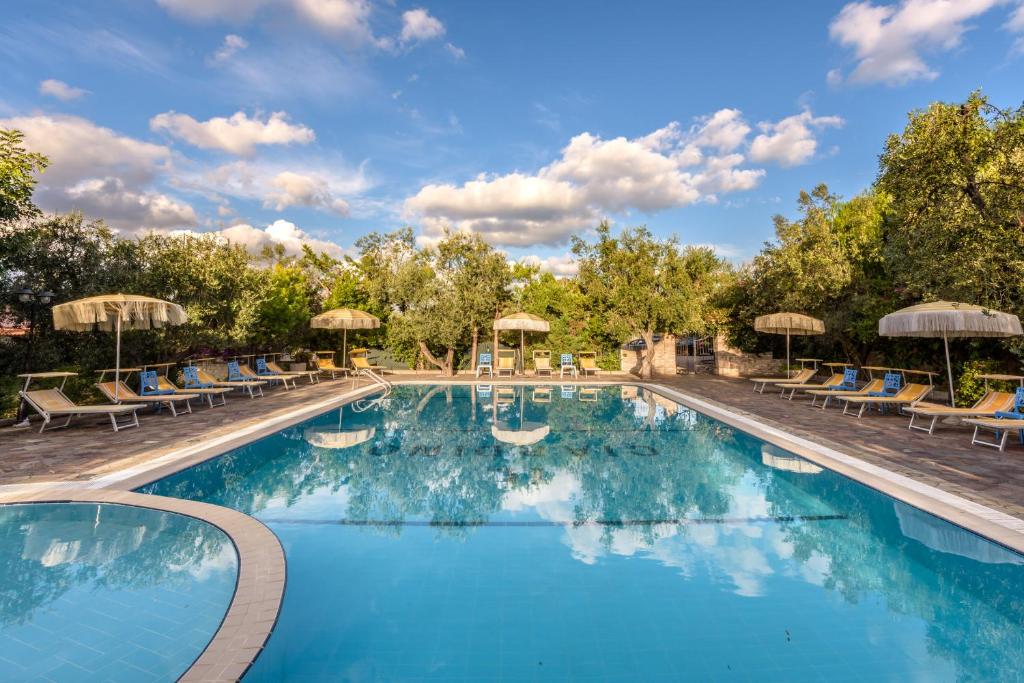 a swimming pool at a resort with chairs and umbrellas at Il Giardino in Foce Varano