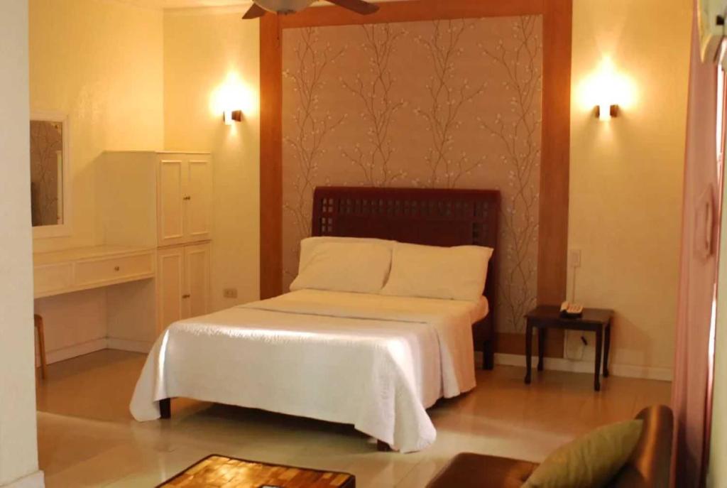 a bedroom with a bed with white sheets and pillows at OYO 1202 Shilla Hotel in Pampang