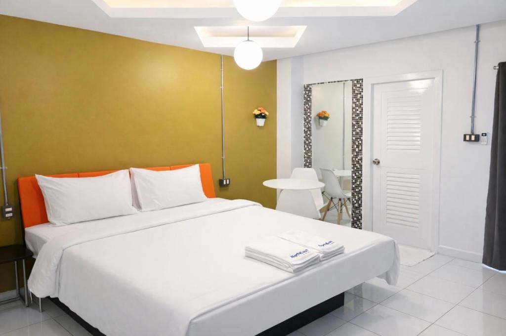 a bedroom with a white bed and a yellow wall at The Northeast Hotel in Si Sa Ket