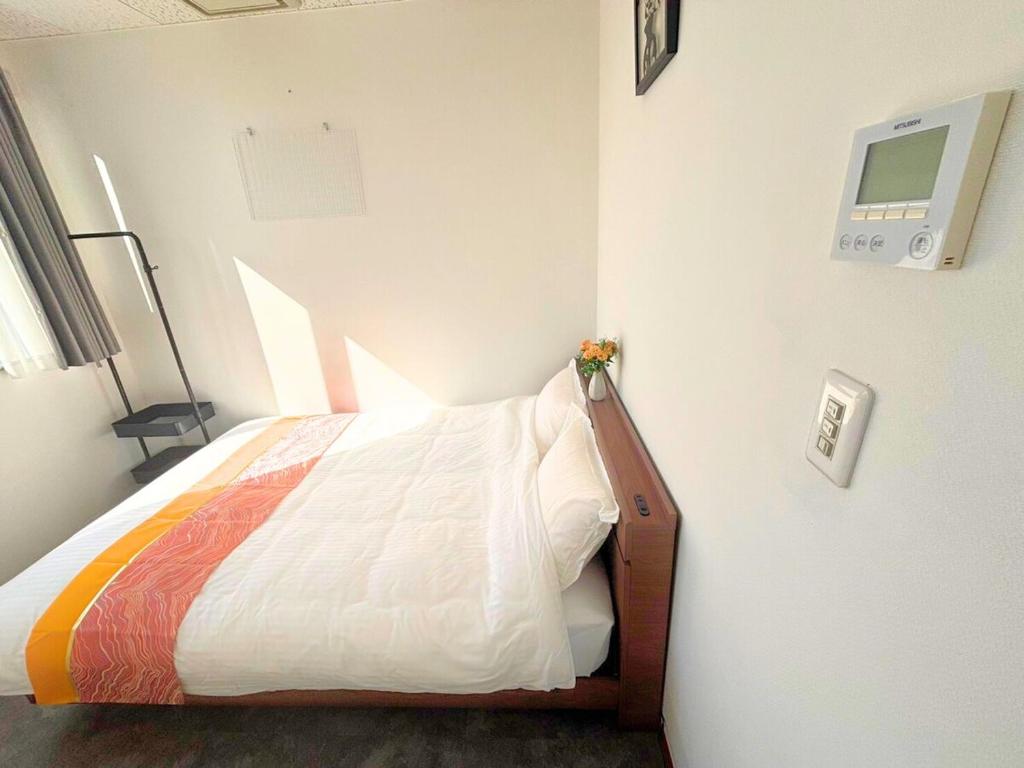 a bedroom with a bed with a tv on the wall at Magokoro House 201 in Nishiizu